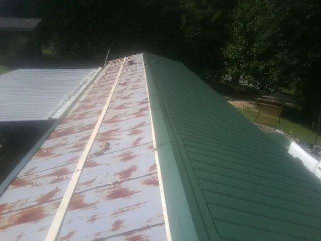 Old rusted panels beside newly installed green metal roofing — Wind Damage Roof Repair by Roofing Brothers in Attleboro Falls