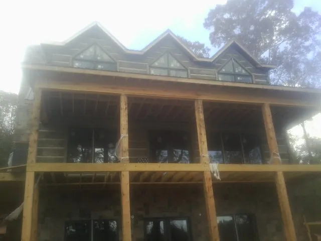 Dormers and porch framing on a large log home under construction — Roof Coating work by our crew in Attleboro Falls