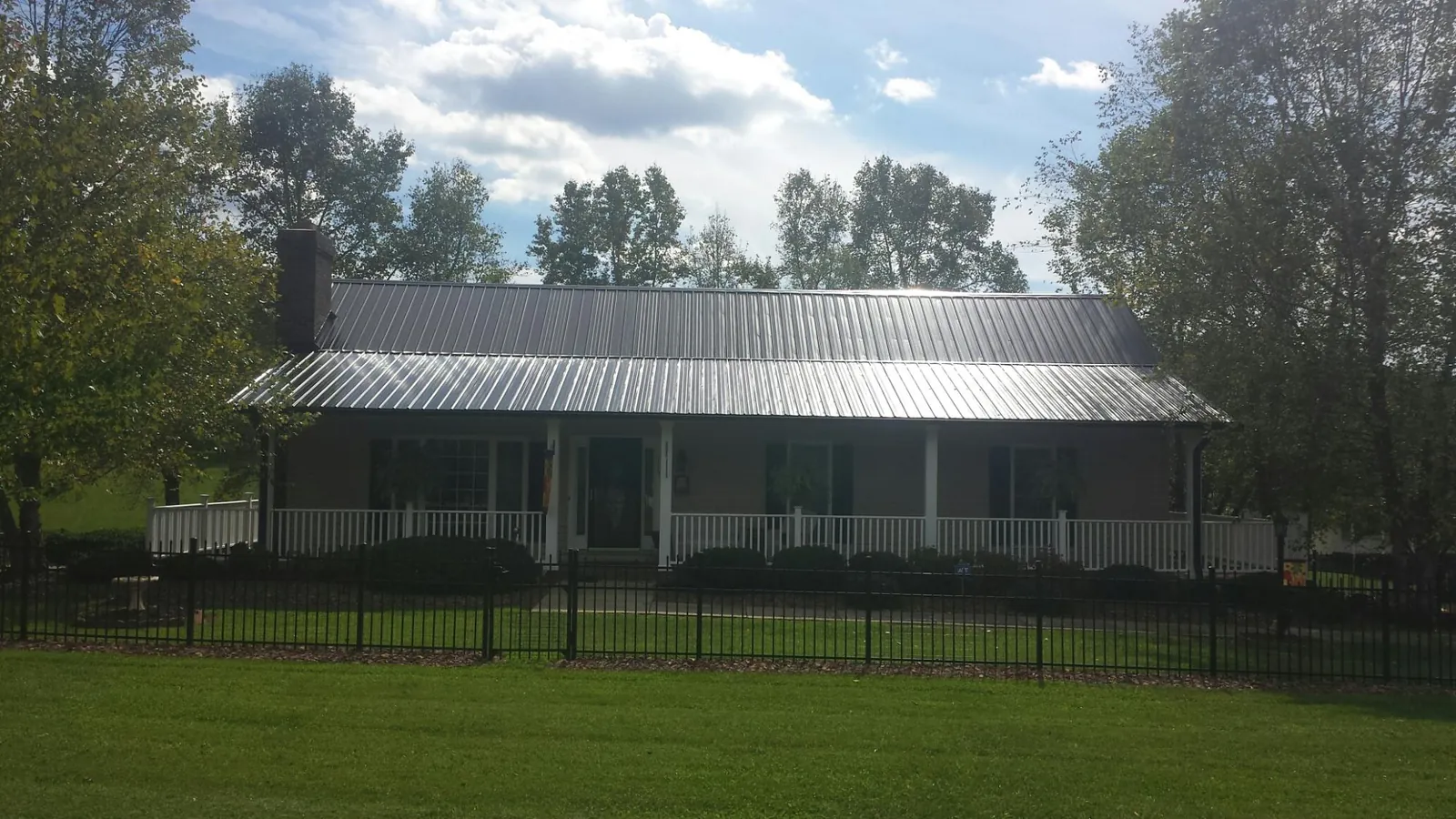 Gray metal roof on a brick ranch with a full width front porch — Gutter Guard Installation work by our crew in Attleboro Falls