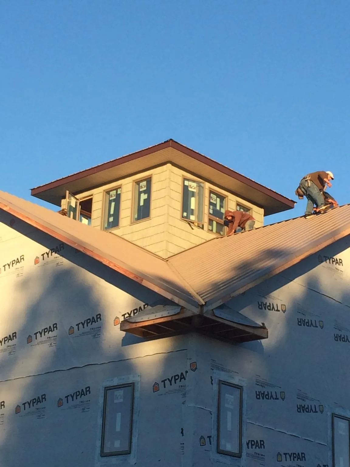 Roofers working around a rooftop cupola on a new metal roof at sunset — Roof Waterproofing in Attleboro Falls by Roofing Brothers